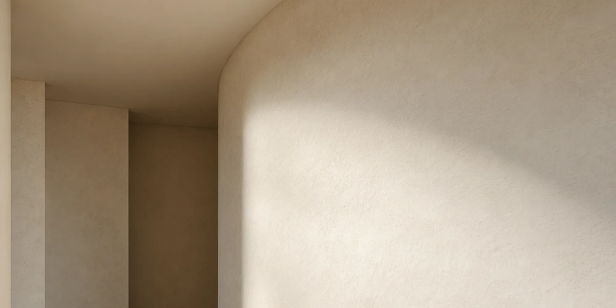 A curved pale plaster wall meeting a polished limestone floor in soft daylight.